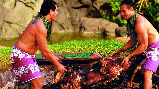 two guys pulling a cooked pig out of ground ready to eat